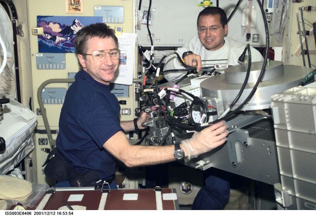 ISS003-E-8406 (12 December 2001) --- Astronauts Frank L. Culbertson, Jr. (left), Expedition Three mission commander, and Daniel W. Bursch, Expedition Four flight engineer, work in the Zvezda Service Module on the International Space Station (ISS). The image was taken with a digital still camera.