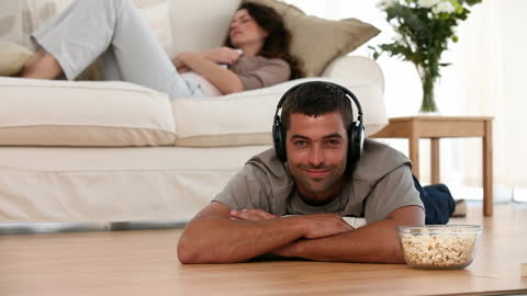 Relaxed Man Enjoys Music in Living Room with Popcorn