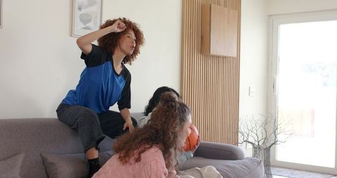 Friends cheering and reacting on couch holding basketball in bright modern living room