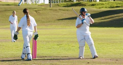 Female Cricketers Relaxing on Pitch by Pink Stumps