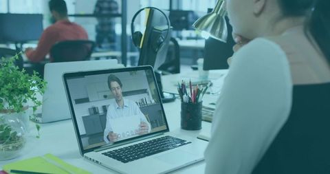 Woman Engaged in Virtual Meeting on Laptop in Modern Office