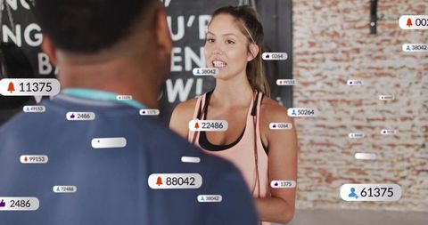 Woman speaking to trainer in urban gym while livestreaming and gaining followers