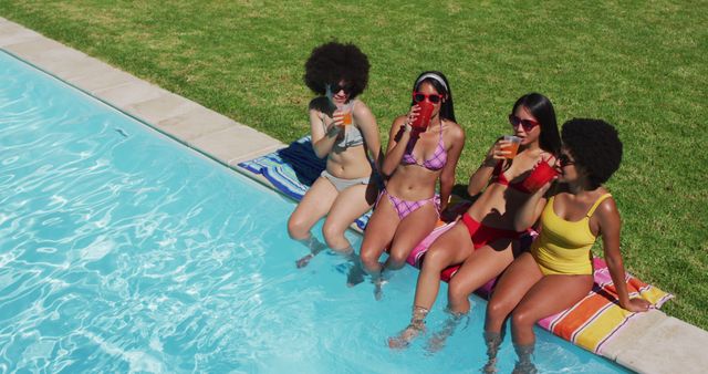 Group of diverse girls enjoying their drinks while sitting by the pool. youth friendship and pool party concept