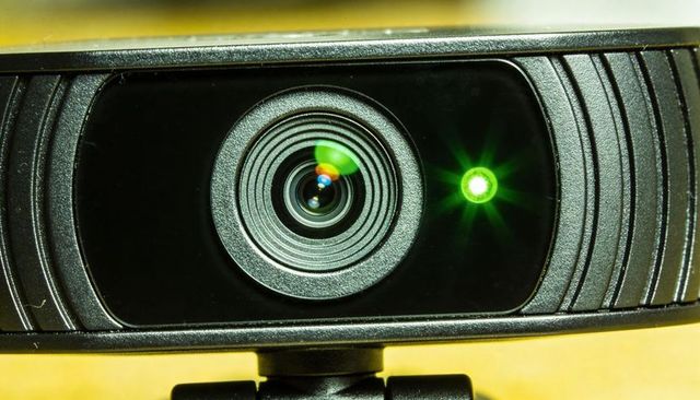 Usb webcam lens showing concentric rings and green led on monitor mount closeup