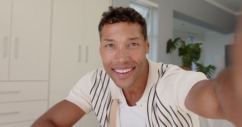 Smiling man taking selfie in modern kitchen interior lighting