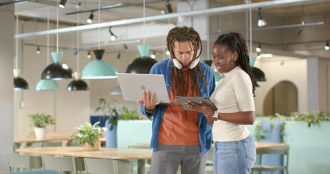 Black professionals collaborating using laptop and tablet in contemporary coworking space