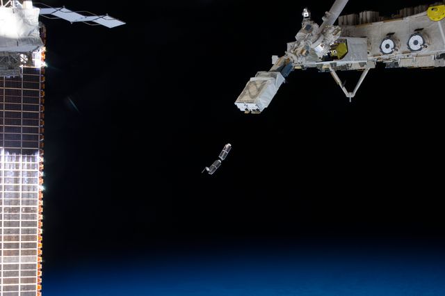 This image features the deployment of NanoRacks CubeSats from the International Space Station (ISS). Taken by an Expedition 38 crew member, it captures the moment when the CubeSats are released by the NanoRacks Launcher attached to the Japanese robotic arm. The ISS solar array panels are partial visible on the left, while Earth's curving horizon is seen in the background. This compelling space exploration scene is suitable for illustrating space technology, satellite missions, robotics, and advanced electronics testing. It can be used in educational materials, publications, and media related to space exploration and scientific experiments.