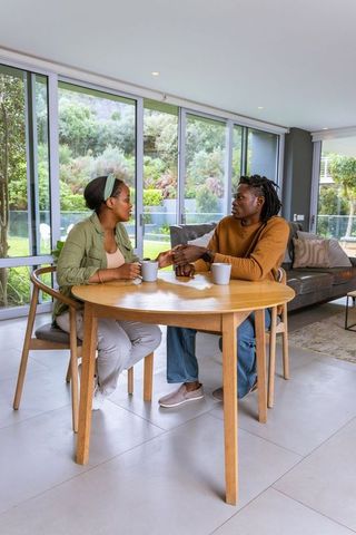 African american couple sharing intimate conversation holding hands at round table in modern home