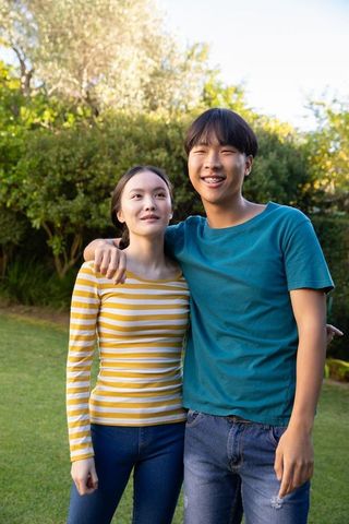 Smiling Young Couple Embracing Outdoors on Sunny Day