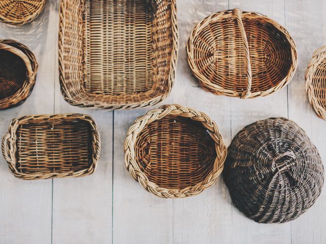 This image showcases a variety of handwoven wicker baskets arranged on a wooden surface. The different shapes and sizes highlight the craftsmanship involved. Ideal for use in home decor blogs, craft tutorials, or as a background for a rustic-themed website.