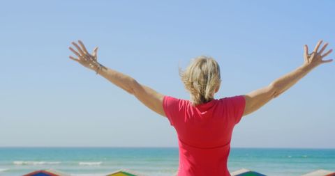 Senior Woman Enjoying Sea View with Outstretched Arms on Sunny Beach - Download Free Stock Images Pikwizard.com