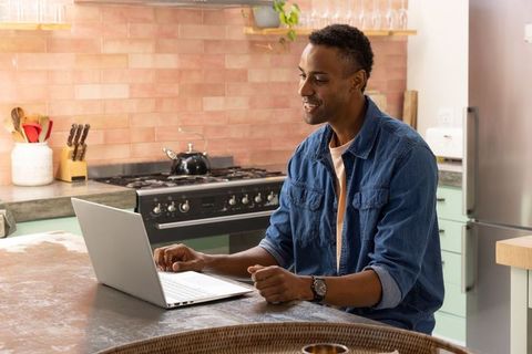 Man Using Laptop at Kitchen Island in Cozy Modern Kitchen