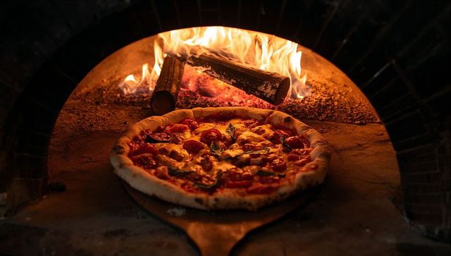 Baking neapolitan pizza in wood-fired brick oven with blistered crust and rustic paddle