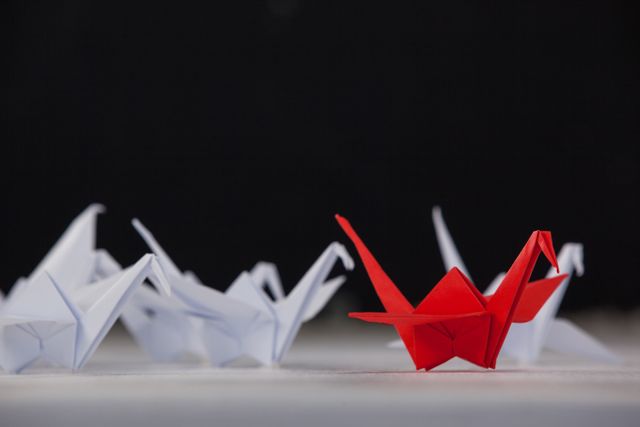 Paper cranes arranged together on white surface