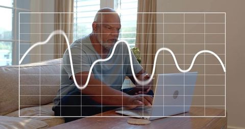 Senior man working on laptop and smartphone in cozy modern living room with graph overlay
