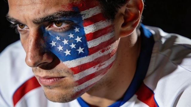 Intense close-up male portrait with american flag face paint conveying patriot determination