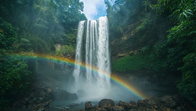 Majestic waterfall with rainbow over lush rainforest