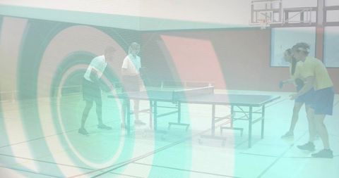 Four players playing doubles table tennis in indoor gym with energetic rally and teamwork