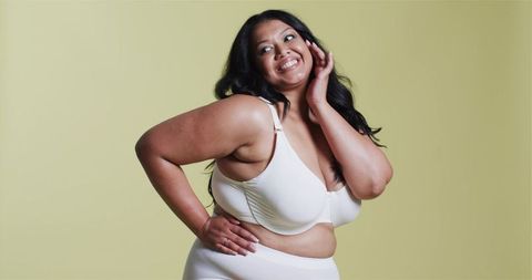 Confident plus size woman in white undergarments on pale green