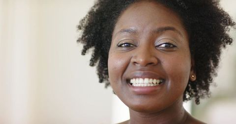 Mid adult african american woman smiling closeup showing gold stud earring and curly hair