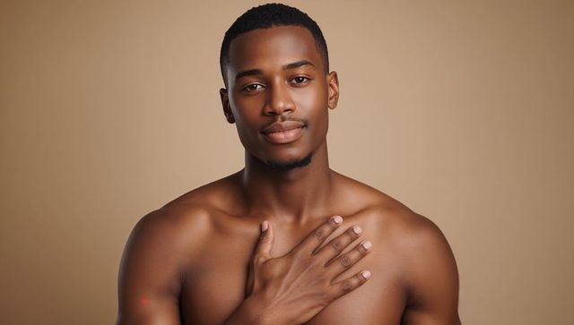 Placing hand on chest bare-chested man gazing calmly portrait wellness skincare selfcare