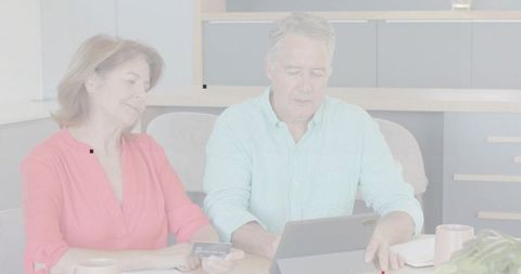 Senior couple using tablet and credit card for online shopping and banking at home