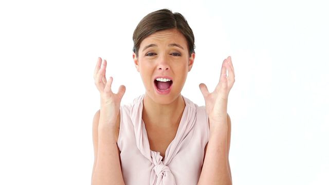 A woman is showing frustration or stress with her hands raised against a white background. This image conveys feelings of exasperation or agitation, making it ideal for illustrating concepts related to stress, emotional struggles, or communicating intense emotions in presentations, articles, or mental health resources.