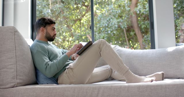 Young Man Relaxing on Sofa and Using Tablet at Home - Download Free Stock Images Pikwizard.com