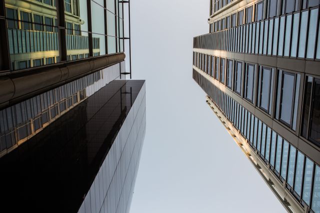This image shows two modern skyscrapers from a low angle, silhouetted against an open sky in a city. The sleek glass structures and clean architectural lines create a sense of contemporary urban development. This can be used for business, real estate, architecture, or city lifestyle themes, ideal for websites, brochures, and presentations.