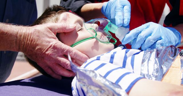 Emergency responders are treating a child with an oxygen mask outdoors. This is suitable for illustrating themes of first aid, quick response, medical support, and healthcare services, especially in outdoor or urgent situations. Can be used in articles and materials on emergency response training, child safety, or healthcare.