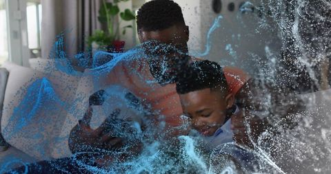 Father holding son on sofa sharing warm hug with blue fluid overlay effect