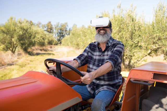 This image depicts a joyful farmer using a virtual reality headset while driving a tractor in a sunny field. It can be used to illustrate the integration of modern technology in agriculture, the joy of innovation, or the blending of traditional farming with new advancements. Ideal for articles on agricultural technology, VR applications, or rural lifestyle.