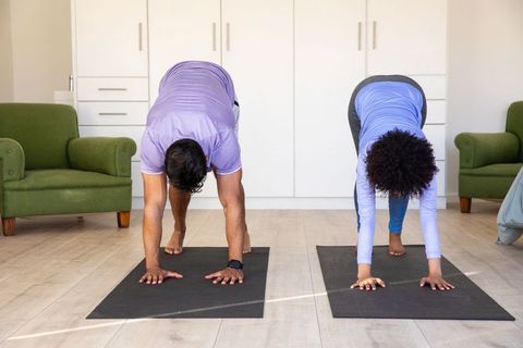 Home Yoga Session with Diverse Couple in Downward Dog Pose
