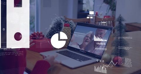Seniors Video Calling on Laptop at Festive Dining Table with Holiday Gifts and Data Charts