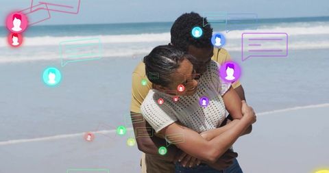 Couple embracing on beach with digital communication graphics