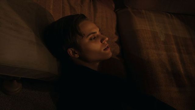 Reclining young man resting on couch in warm moody light for intimate portrait
