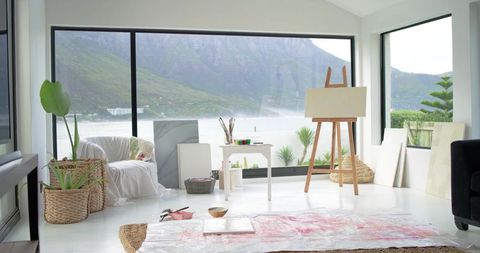Waterfront art studio overlooking misty lake and mountains, easel, paint table, plants