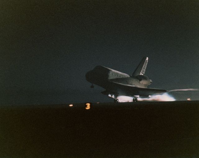 Space Shuttle Discovery achieves nocturnal landing at Kennedy Space Center, Florida, after successful 10-day mission servicing Hubble Space Telescope. Astounding image captures return at night, highlighting shuttle's rear propulsion lighting. Ideal for space exploration articles, NASA mission retrospectives, educational astronomy materials.
