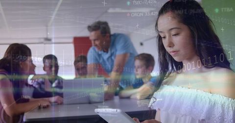 Teen Holding Tablet in Classroom Collaborating with Teacher and Peers Using Technology