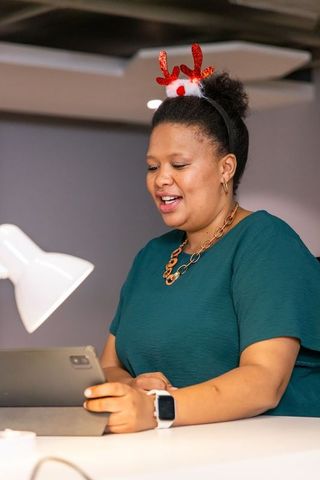 African american businesswoman wearing reindeer antlers presenting on tablet during virtual holiday