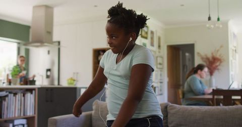 Joyful African American Girl Dancing in Living Room with Earphones