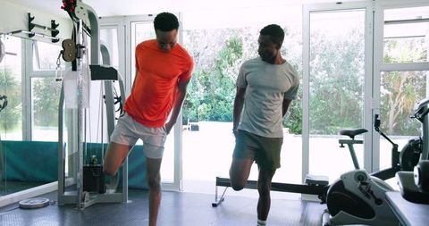 Two Men Practicing Stretching Exercises in a Gym Setting