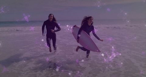Running surf duo carrying pink shortboards through shallow waves with purple light overlay