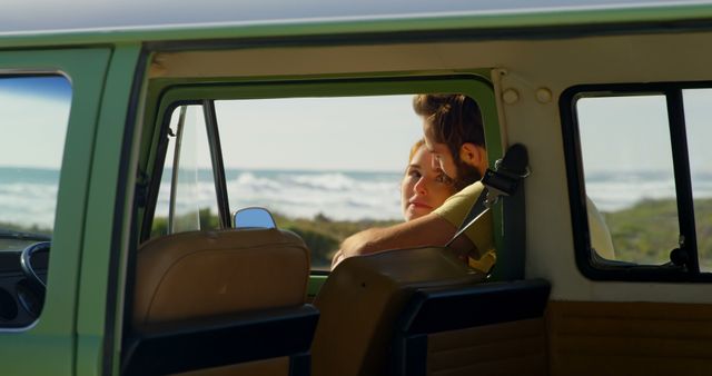 Couple embracing inside vintage van with the coastal scenery visible through open windows. Used for concepts of travel, romance, adventure, and leisure. Ideal for promoting road trips, couple getaways, and lifestyle content.
