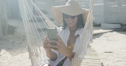 Woman Relaxing on Beach Hammock Using Smartphone