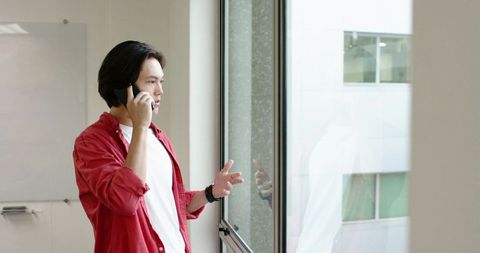 Professional asian man on smartphone by office window