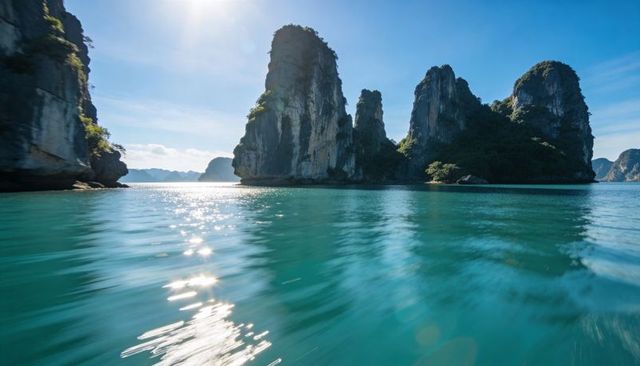 Sunlit karst towers rising from turquoise bay, sparkling sea reflecting limestone cliffs