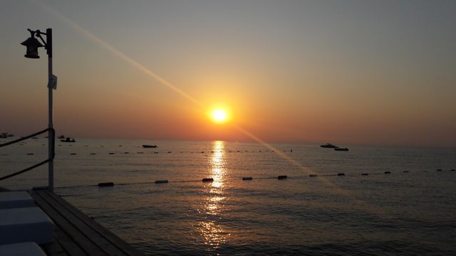 Tranquil Sunset Over Calm Sea with Boats in Distance - Download Free Stock Photos Pikwizard.com