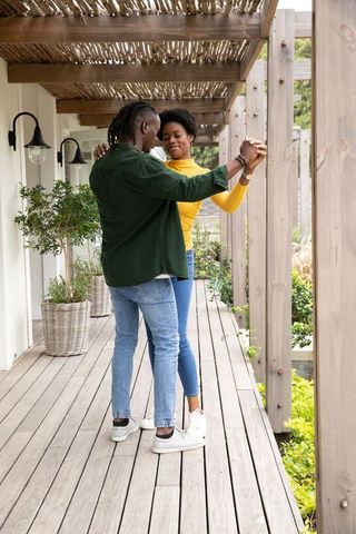 Romantic african american couple dancing on elegant pergola deck