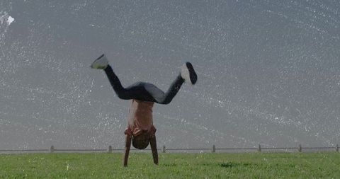 Young Boy Performing Handstand on Green Field